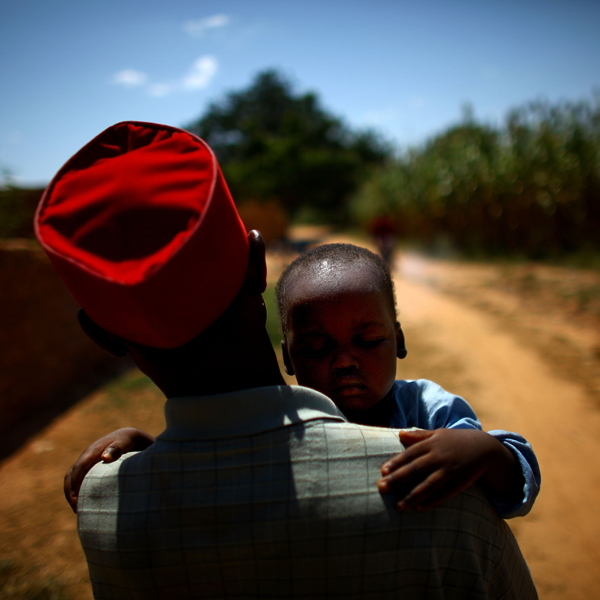 Ado Ibrahim carries his son Aminu through a village in northern Nigeria. Aminu was paralyzed by polio in August.