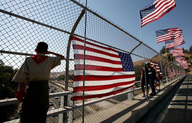 A Boy Scout salutes traffic as he stands next to a flag display on a freeway overpass September 11, 2008 in Lafayette, California.