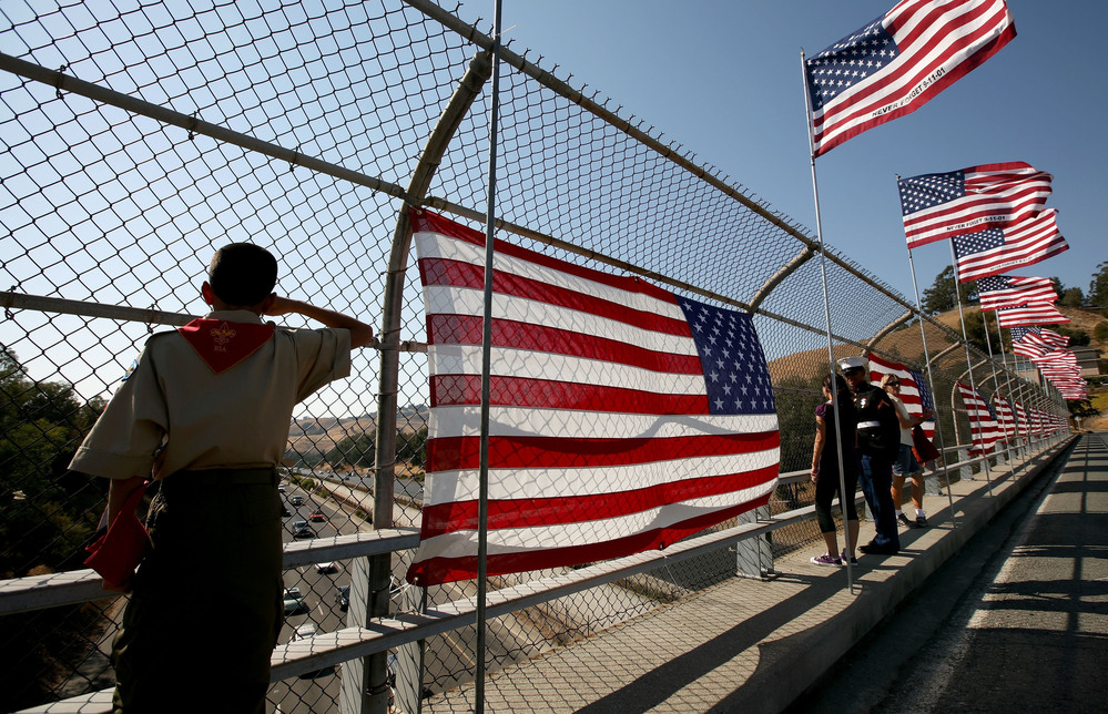 A Boy Scout salutes traffic as he stands next to a flag display on a freeway overpass September 11, 2008 in Lafayette, California.