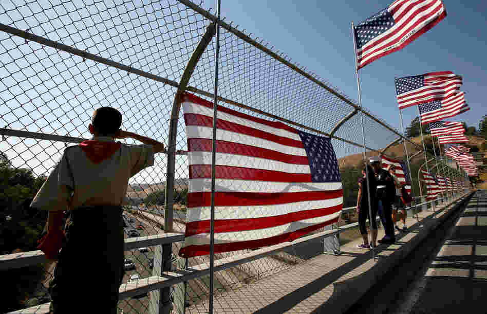A Boy Scout salutes traffic as he stands next to a flag display on a freeway overpass September 11, 2008 in Lafayette, California.