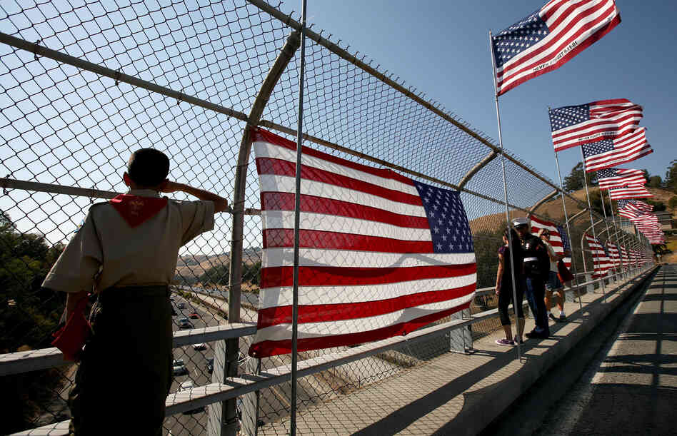 A Boy Scout salutes traffic as he stands next to a flag display on a freeway overpass September 11, 2008 in Lafayette, California.