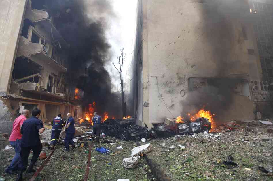 Lebanese firefighters extinguish burning cars in Beirut following a huge bomb explosion.