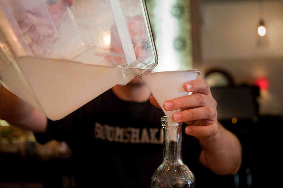 He pours the mixture into a serving bottle.