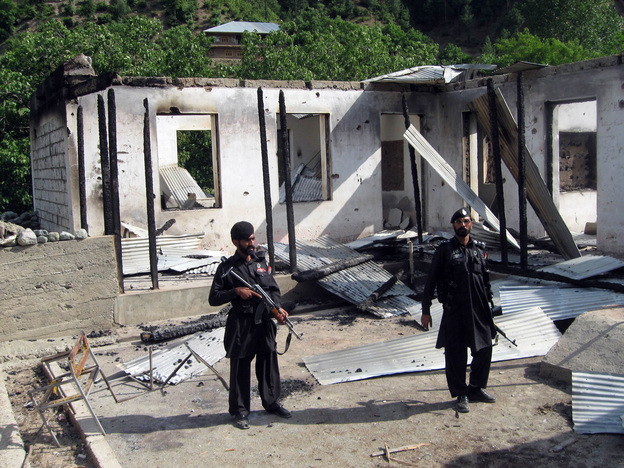 Pakistani security personnel stand guard in front of a burnt-out school following an attack by the Pakistani Taliban in the northwestern district of Upper Dir in June 2011. The Taliban have destroyed many schools in northwestern Pakistan.