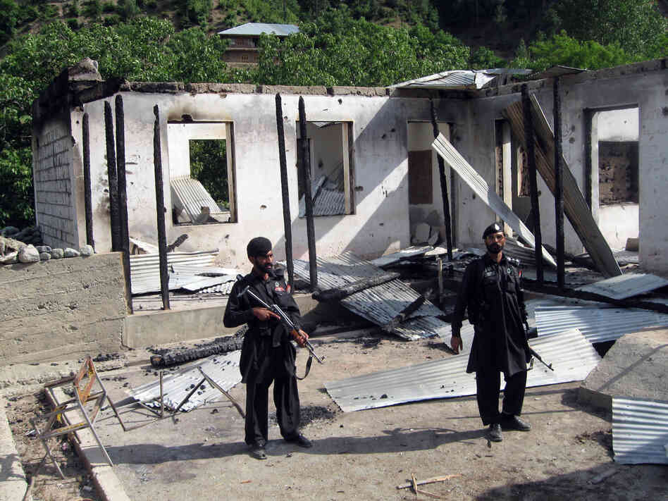 Pakistani security personnel stand guard in front of a burnt-out school following an attack by the Pakistani Taliban in the northwestern district of Upper Dir in June 2011. The Taliban have destroyed many schools in northwestern Pakistan.