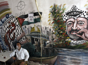 A Palestinian man smokes a nargileh (waterpipe) next to a mural of the late Palestinian leader Yasser Arafat in a coffee shop in the West Bank city of Jenin in September.