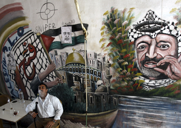 A Palestinian man smokes a nargileh (waterpipe) next to a mural of the late Palestinian leader Yasser Arafat in a coffee shop in the West Bank city of Jenin in September.
