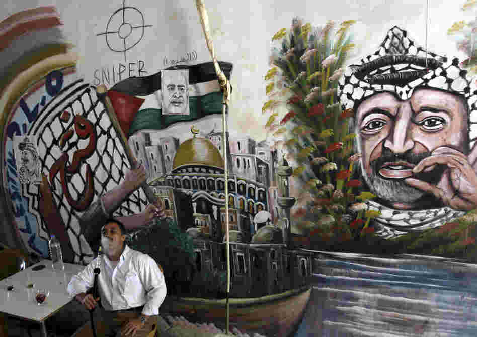 A Palestinian man smokes a nargileh (waterpipe) next to a mural of the late Palestinian leader Yasser Arafat in a coffee shop in the West Bank city of Jenin in September.