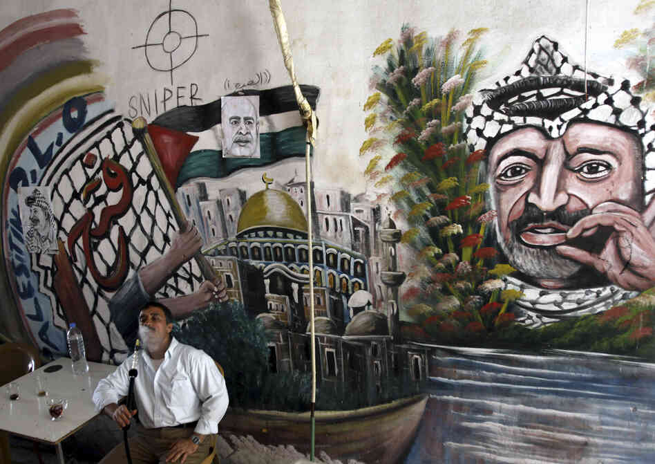 A Palestinian man smokes a nargileh (waterpipe) next to a mural of the late Palestinian leader Yasser Arafat in a coffee shop in the West Bank city of Jenin in September.