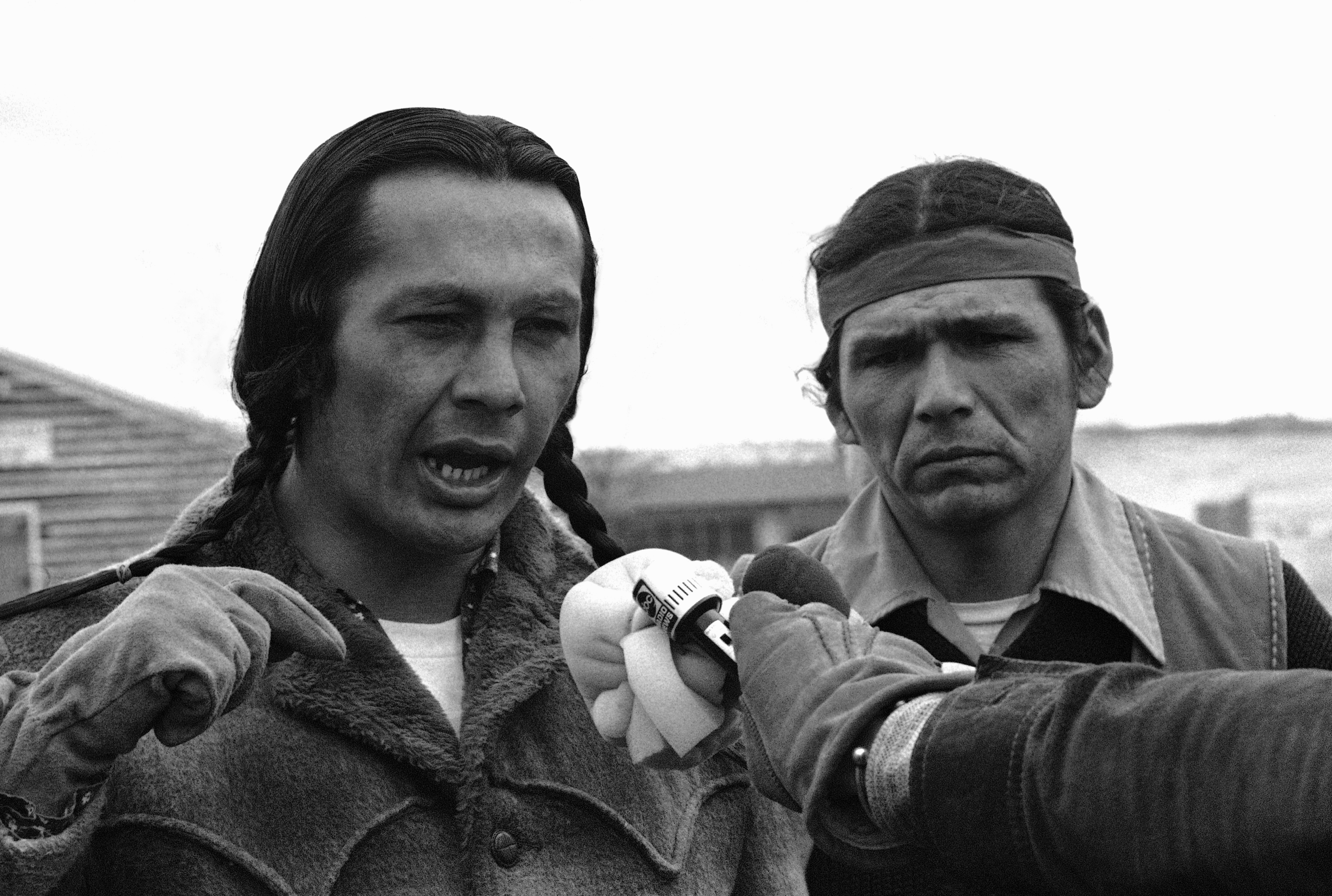 Russell Means, left, talks to media in 1973 in the village of Wounded Knee, South Dakota.