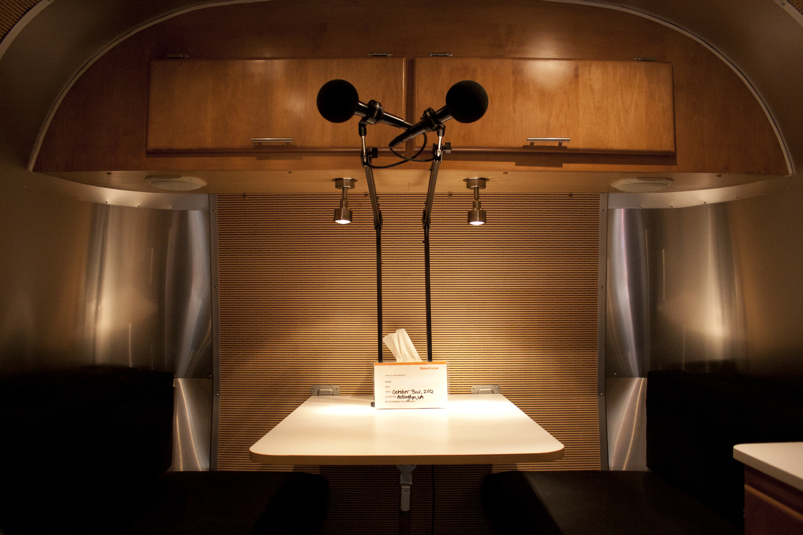 An inside look of the trailer's soundproof recording studio. Below the microphones is a card for the participants' information and a box of tissues.