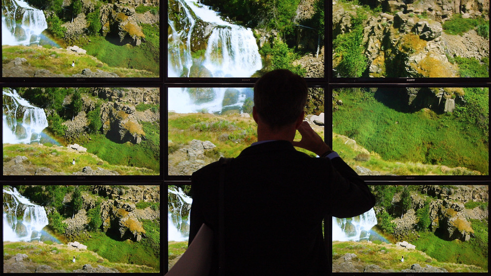 A visitor looks at a bank of TV screens at a consumer electronics show in Berlin. While TV and movies are available on many devices, consumers often struggle to find exactly what they want, television critic Eric Deggans says.