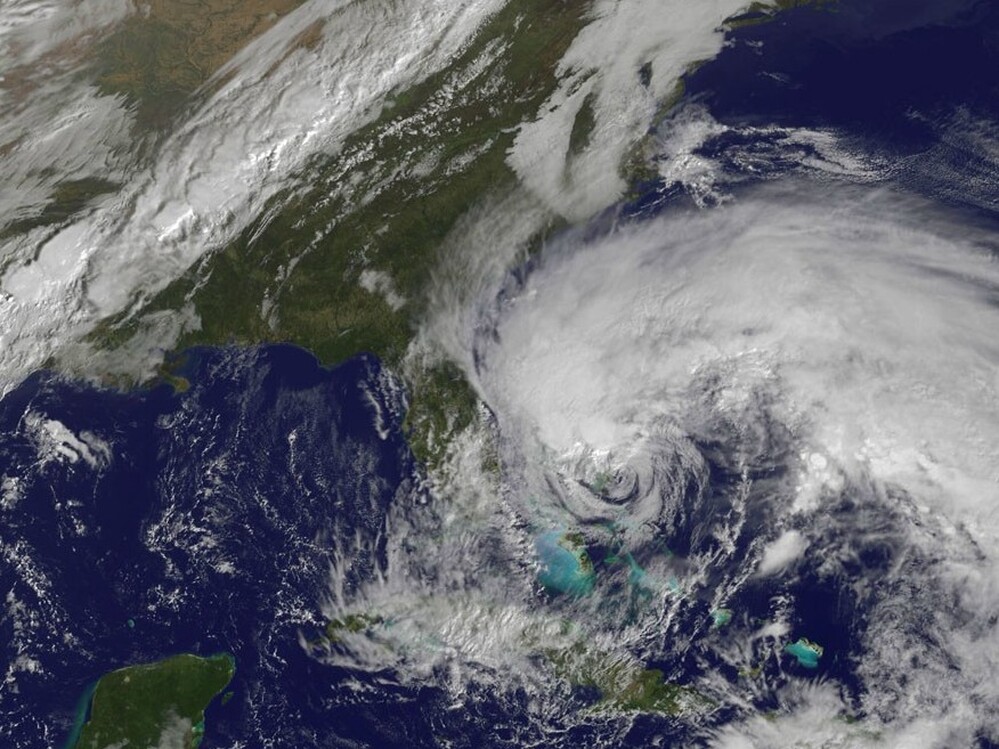 In this satellite image provided Friday by the National Oceanic and Atmospheric Administration, Hurricane Sandy's huge cloud extent of up to 2,000 miles churns over the Bahamas, as a line of clouds associated with a powerful cold front approaches the East Coast of the U.S.