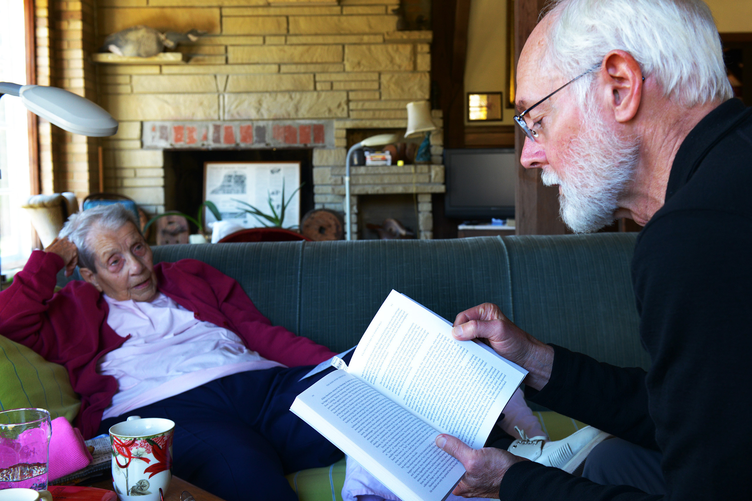 Margaret Zerwekh, who has lived in the mill house for half a century, listens to Milton Bates read from his book, Bark River Chronicles. Zerwekh's home is a treasure trove of Delafield history. 