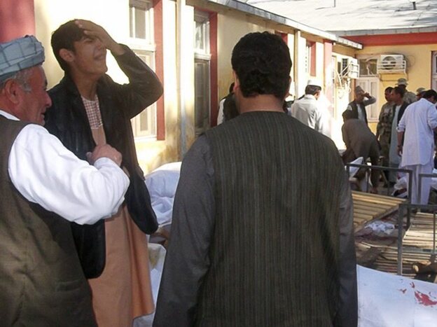Men mourn beside the bodies of victims from today's suicide bomb attack in Maymana, Afghanistan.