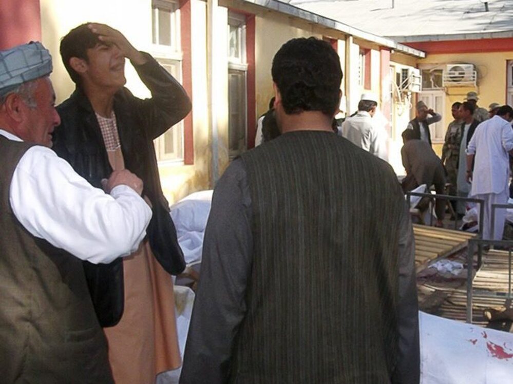 Men mourn beside the bodies of victims from today's suicide bomb attack in Maymana, Afghanistan.