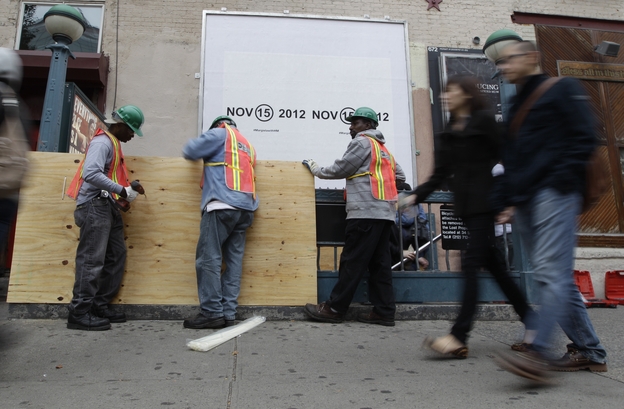 Workers cover an entrance with plywood at a subway station in New York City in preparation for flooding from Hurricane Sandy.