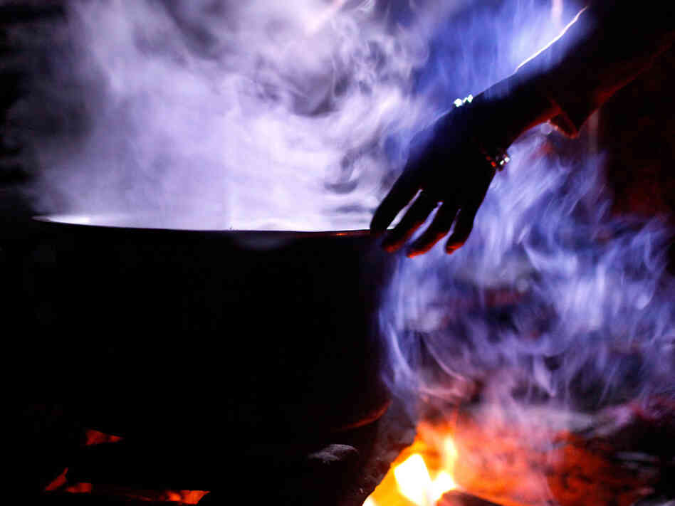 A woman boils water in a pot for cooking. All of the food consumed during the blood-drinking festival must be brought up to the campsite from the village of Marpha below. The trek uphill takes about four hours.