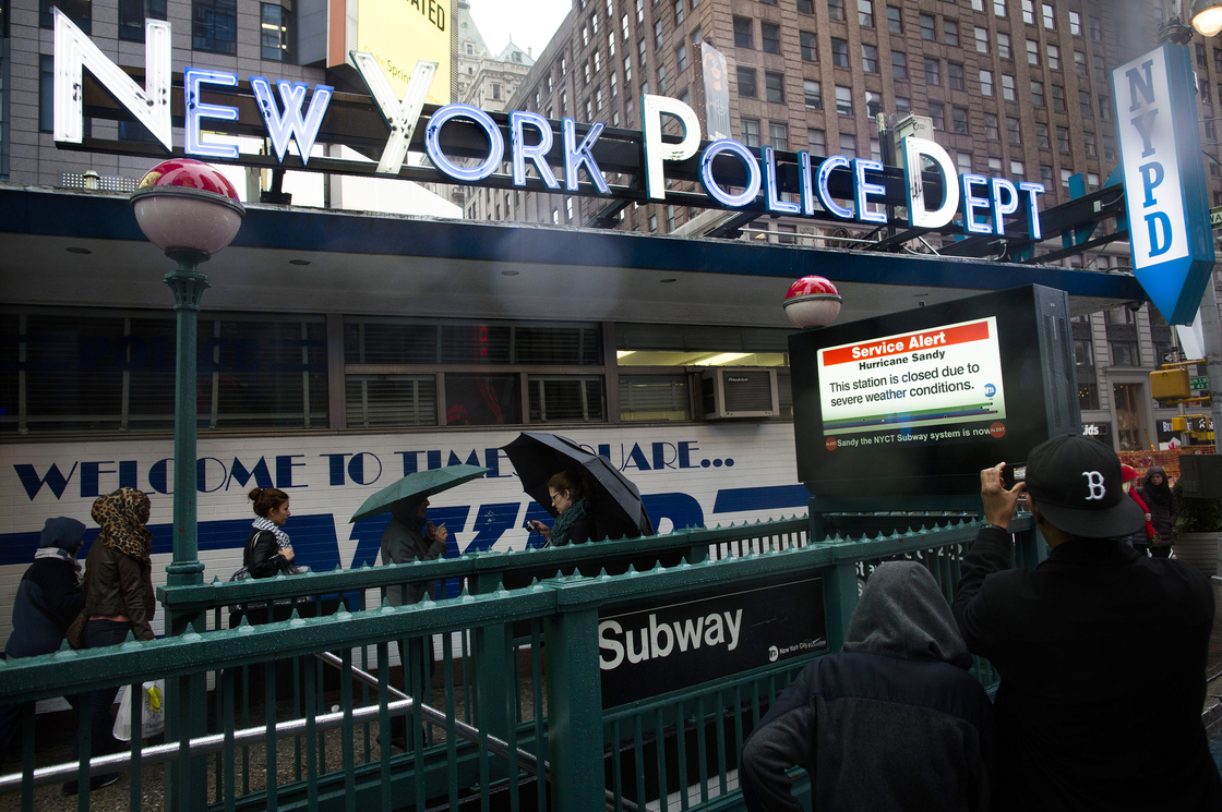 Pedestrians pass a New York Police Department station beside a closed subway entrance at Times Square on Monday.