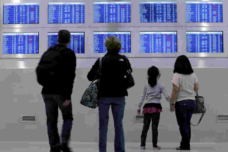 Travelers on Delta Airlines look at a departure screen in Detroit as dozens of departing flights have been canceled.