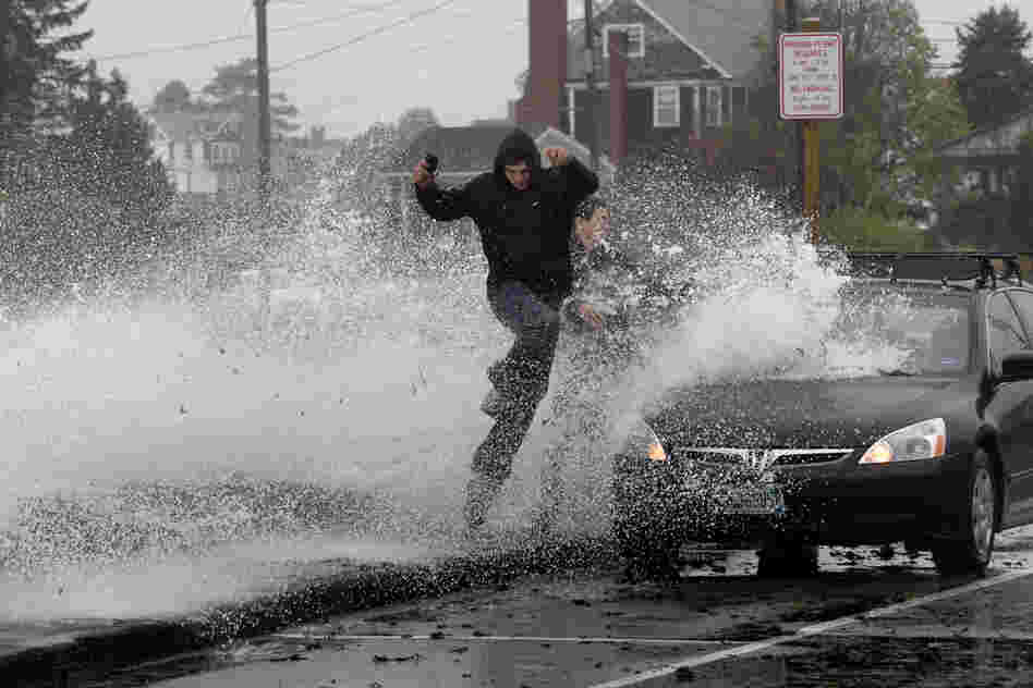 Caleb Lavoie (front) and Curtis Huard leap into the street as a large wave crashes over a seawall on the Atlantic Ocean in Kennebunk, Maine.