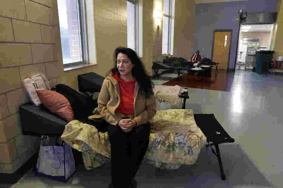 Diana Clarke sits on a cot set up by the Red Cross as she takes shelter from Hurricane Sandy at Weymouth High School in Weymouth, Mass.