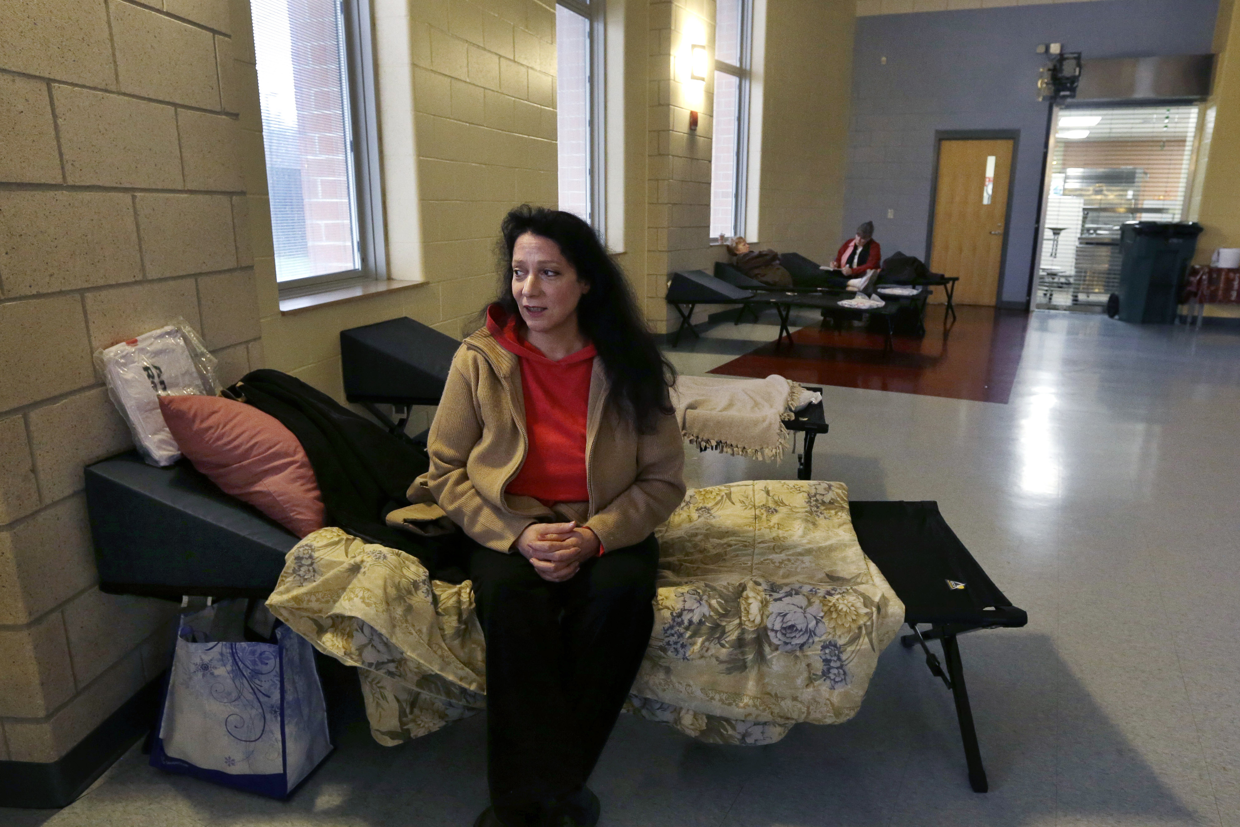 Diana Clarke sits on a cot set up by the Red Cross as she takes shelter from Hurricane Sandy at Weymouth High School in Weymouth, Mass.