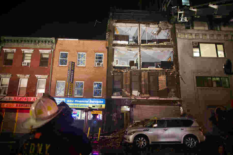 Firefighters look up at the facade of a four-story building that collapsed onto the sidewalk in New York City. As of 7 p.m. ET Monday, Sandy had been reclassified as a "post-tropical cyclone."