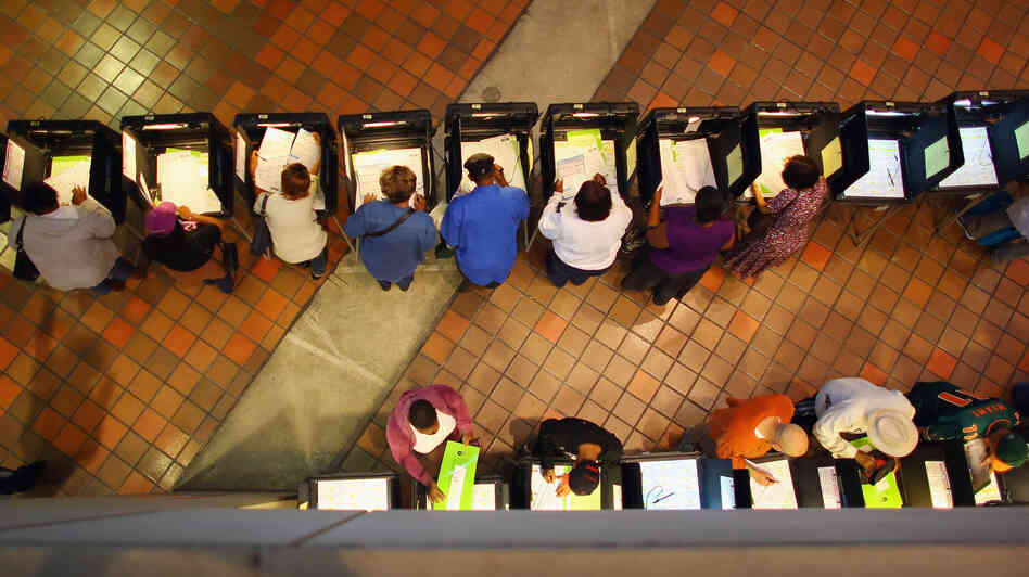 Early voters fill out ballots in Miami. Voting experts say Hurricane Sandy isn't likely to cause major disruptions — but that it would have been a far different matter had Florida taken a direct hit from the storm.