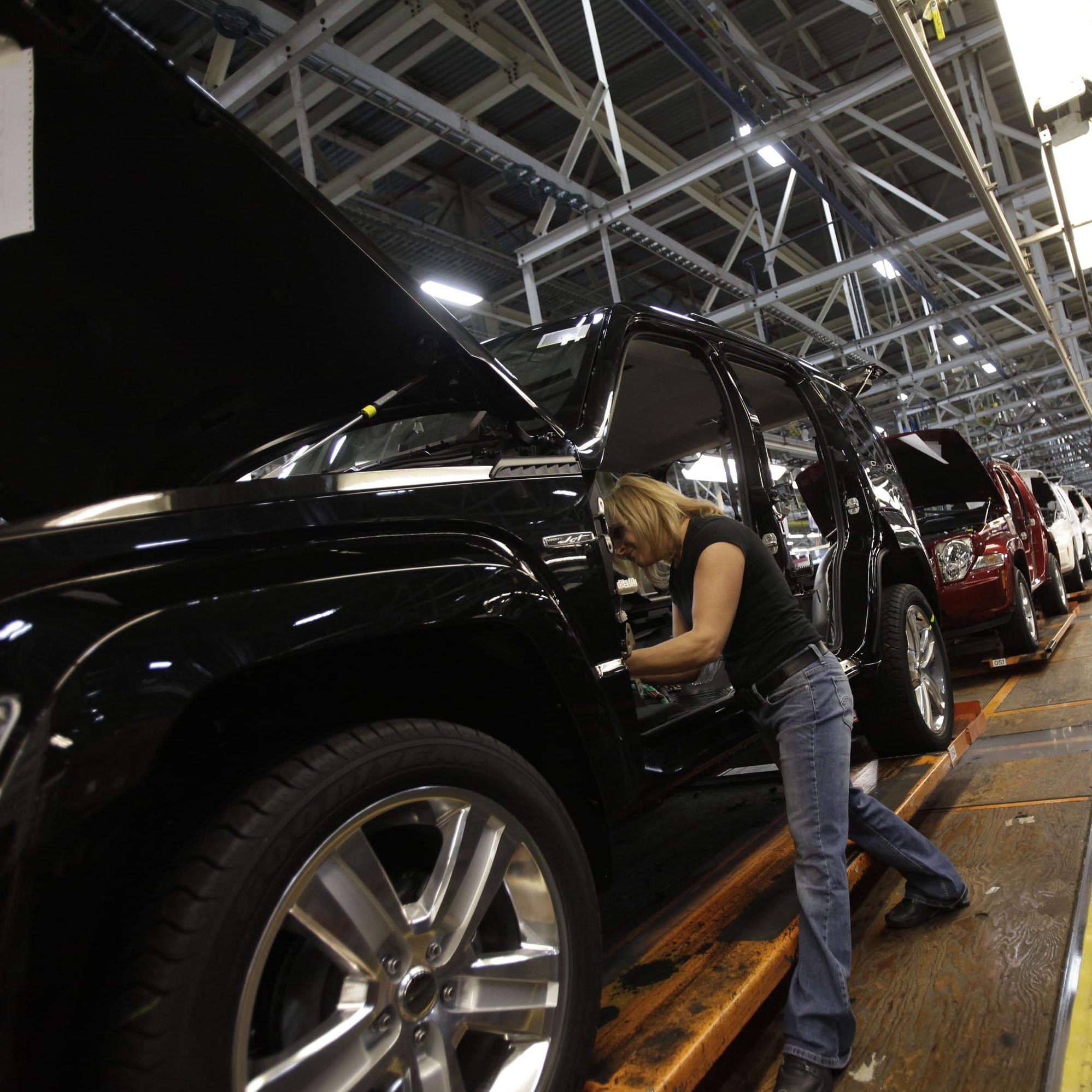 A worker installs carpet into a Jeep Liberty at the Toledo Assembly Complex in Toledo, Ohio, in 2011.