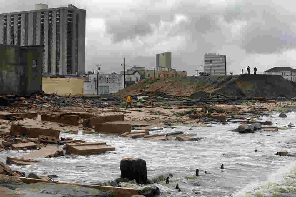 In Atlantic City, NJ, people stand on a mound of construction dirt to view the area where a 2,000-foot section of the 'uptown' boardwalk was destroyed by flooding from Hurricane Sandy. The storm has claimed more than 30 lives and has caused massive flooding across much of the Atlantic seaboard.