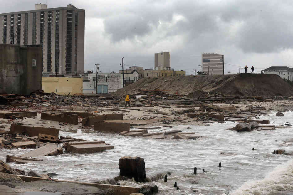 In Atlantic City, NJ, people stand on a mound of construction dirt to view the area where a 2,000-foot section of the 'uptown' boardwalk was destroyed by flooding from Hurricane Sandy. The storm has claimed more than 30 lives and has caused massive flooding across much of the Atlantic seaboard.
