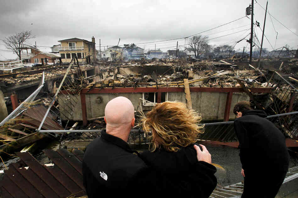 Robert Connolly, left, embraces his wife Laura as they survey the remains of her parent's home that burned to the ground in the Breezy Point section of Queens, N.Y. More than 50 homes were destroyed in the fire which swept through the oceanfront community during Superstorm Sandy. At right is their son, Kyle.