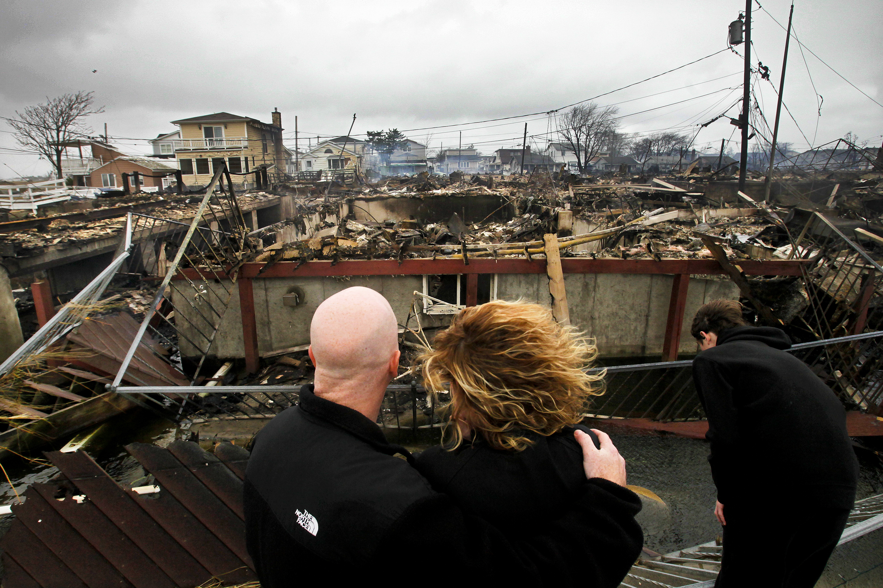 Robert Connolly, left, embraces his wife Laura as they survey the remains of her parent's home that burned to the ground in the Breezy Point section of Queens, N.Y. More than 50 homes were destroyed in the fire which swept through the oceanfront community during Superstorm Sandy. At right is their son, Kyle.