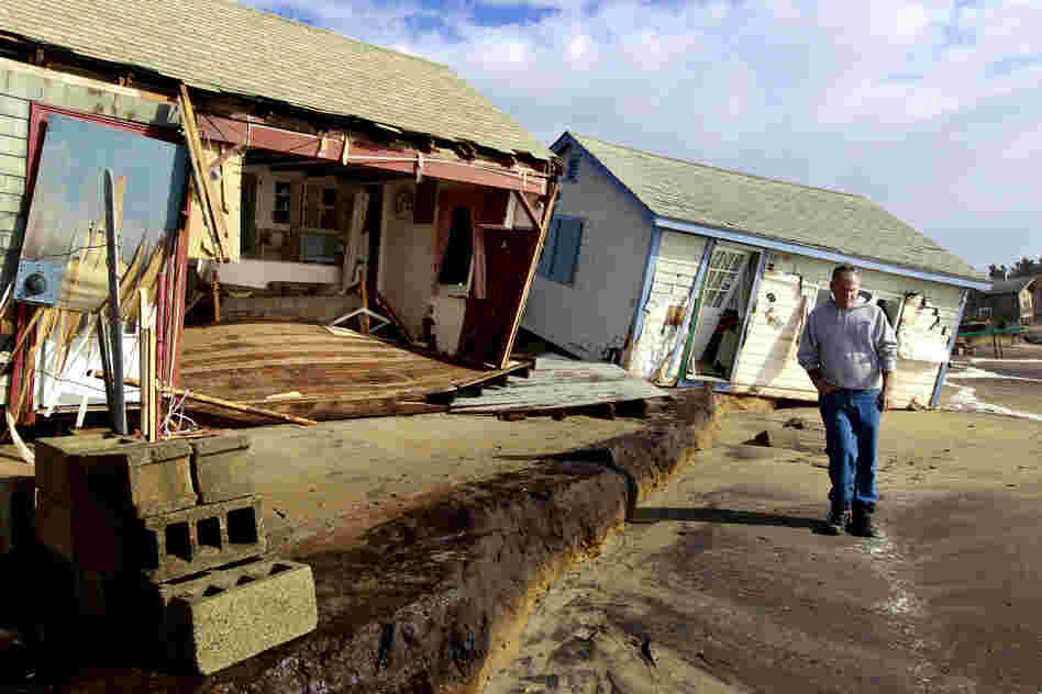 A man walks past cottages damaged by Sandy on Roy Carpenter's Beach in the village of Matunuck, in South Kingstown, R.I.