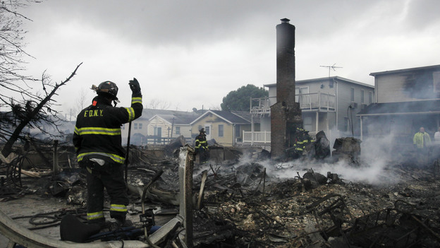 A firefighter surveys the smoldering ruins of a house in the Breezy Point section of New York. (AP)