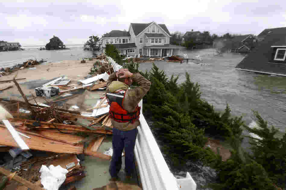 Brian Hajeski, 41, of Brick, N.J., reacts as he looks at debris of a home that washed up on to the Mantoloking Bridge in Mantoloking, N.J. Storm damage has halted mass transit and cut power to more than 6 million homes and businesses.