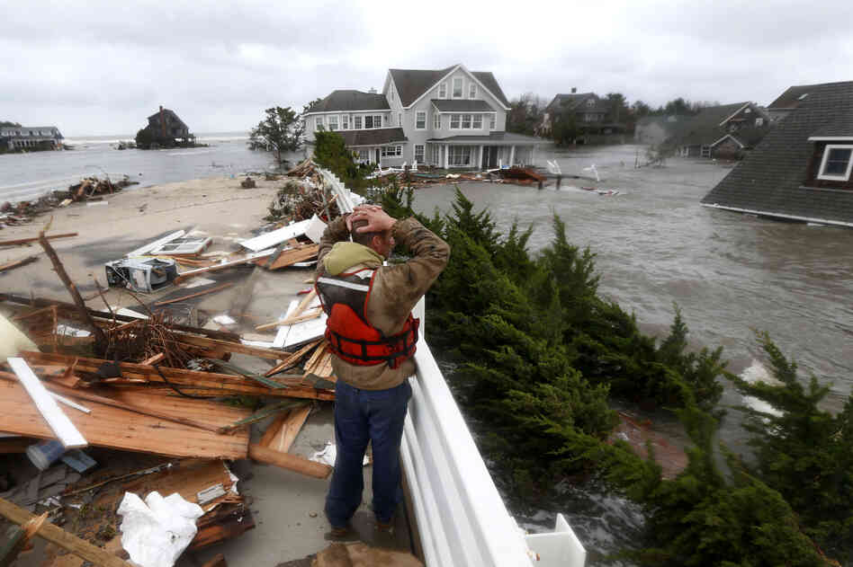 Brian Hajeski, 41, of Brick, N.J., reacts as he looks at debris of a home that washed up on to the Mantoloking Bridge in Mantoloking, N.J. Storm damage has halted mass transit and cut power to more than 6 million homes and businesses.
