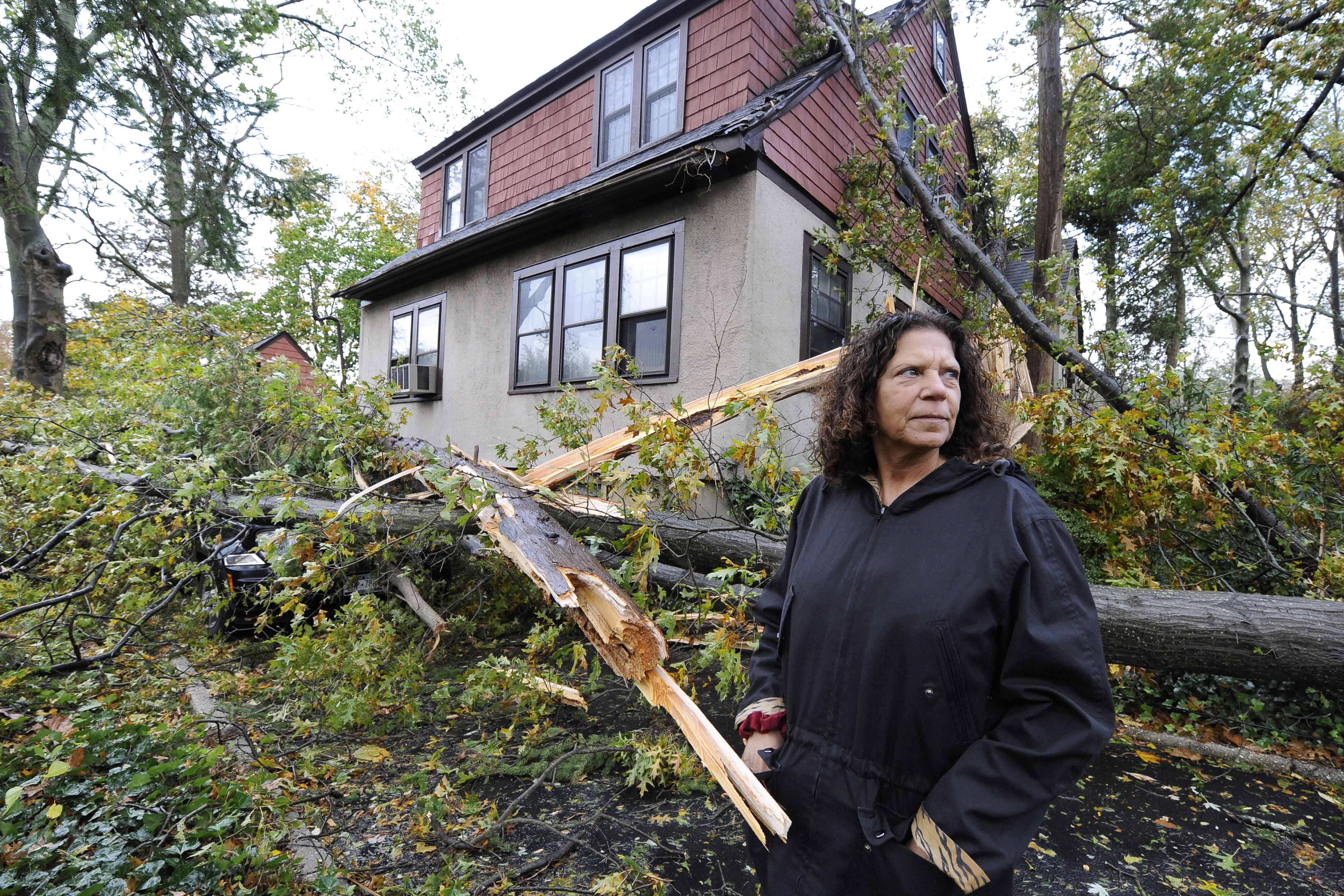 Arlene O'Dell stands in front of her home where several trees fell, one crushing her car, as a result of the powerful winds and rain of Superstorm Sandy on Tuesday in Sea Cliff, N.Y.