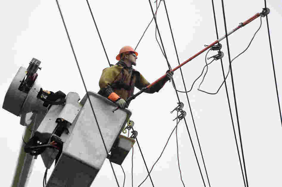 A crewman works on grounding power lines damaged when a large tree was blown down in Falls Church, Va.