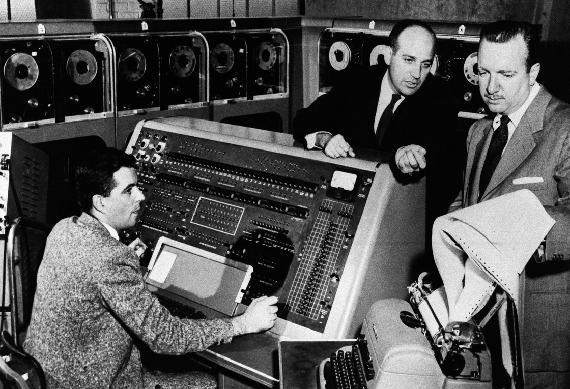 Walter Cronkite (right) listens as Dr. J. Presper Eckert (center) describes the functions of the UNIVAC I computer he helped develop in the early 1950s.