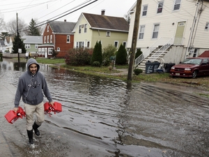 Christian Codorniu carries gas containers Tuesday to fill a home generator following the superstorm in Little Ferry, N.J.