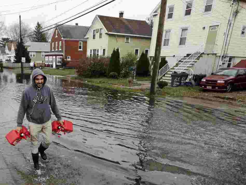 Christian Codorniu carries gas containers Tuesday to fill a home generator following the superstorm in Little Ferry, N.J.