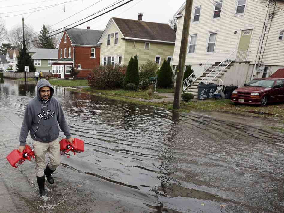 Christian Codorniu carries gas containers Tuesday to fill a home generator following the superstorm in Little Ferry, N.J.