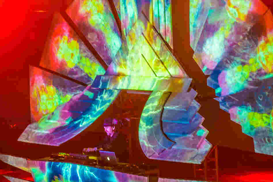 The English psych-ambient performer Shpongle performs at a sort of rainbow-colored throne.
