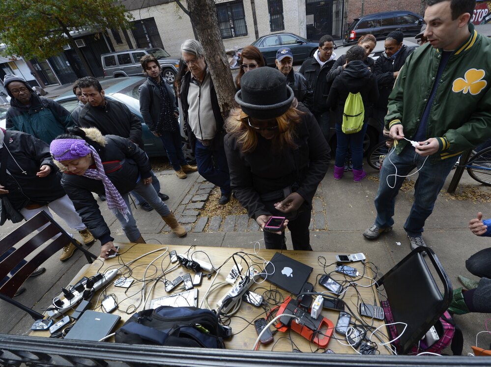 People wait to charge cellphones and laptops Thursday at a generator set up in the West Village. Superstorm Sandy left large parts of New York City without power.