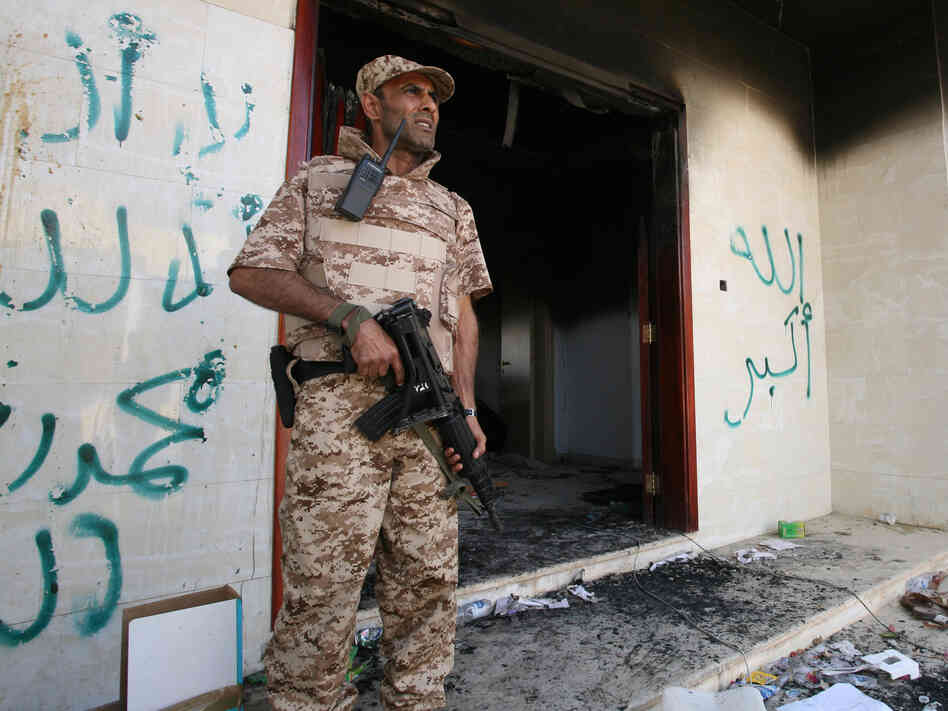 A Libyan military guard stands in front of one of the U.S. Consulate's burned out buildings on Sept. 14. The U.S. is offering new details of the attack on the consulate that killed four Americans, including Ambassador Chris Stevens.