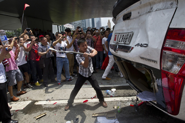 As part of a demonstration against Japan, a Chinese protester destroys a Japanese-model police car in Shenzhen in southern China on Aug. 19.