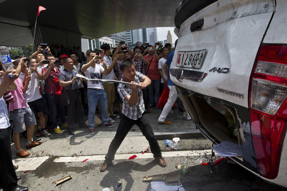 As part of a demonstration against Japan, a Chinese protester destroys a Japanese-model police car in Shenzhen in southern China on Aug. 19.