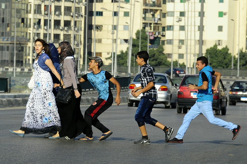 A young Egyptian man grabs a woman crossing the street with her friends in Cairo in August. Vigilante groups are now taking to the streets and spray painting the clothes of the harassers.